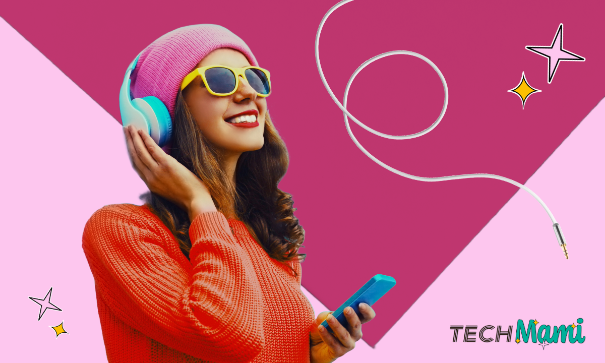 Eine junge Frau in einem leuchtend roten Pullover und einer rosa Mütze genießt Musik über große, bunte Kopfhörer. Sie trägt gelbe Sonnenbrillen und hält ein Smartphone in der Hand. Der Hintergrund ist lebhaft rosa gestaltet, und das TechMami-Logo mit dekorativen Sternen schmückt die obere Ecke.